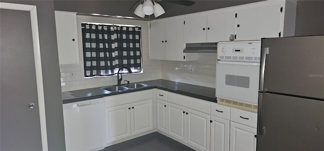 kitchen with under cabinet range hood, white appliances, dark countertops, and white cabinets