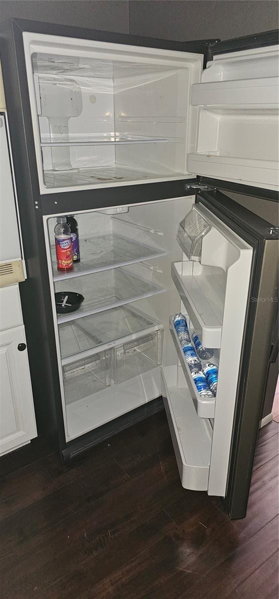 interior details with dark wood-style floors, white cabinetry, and fridge