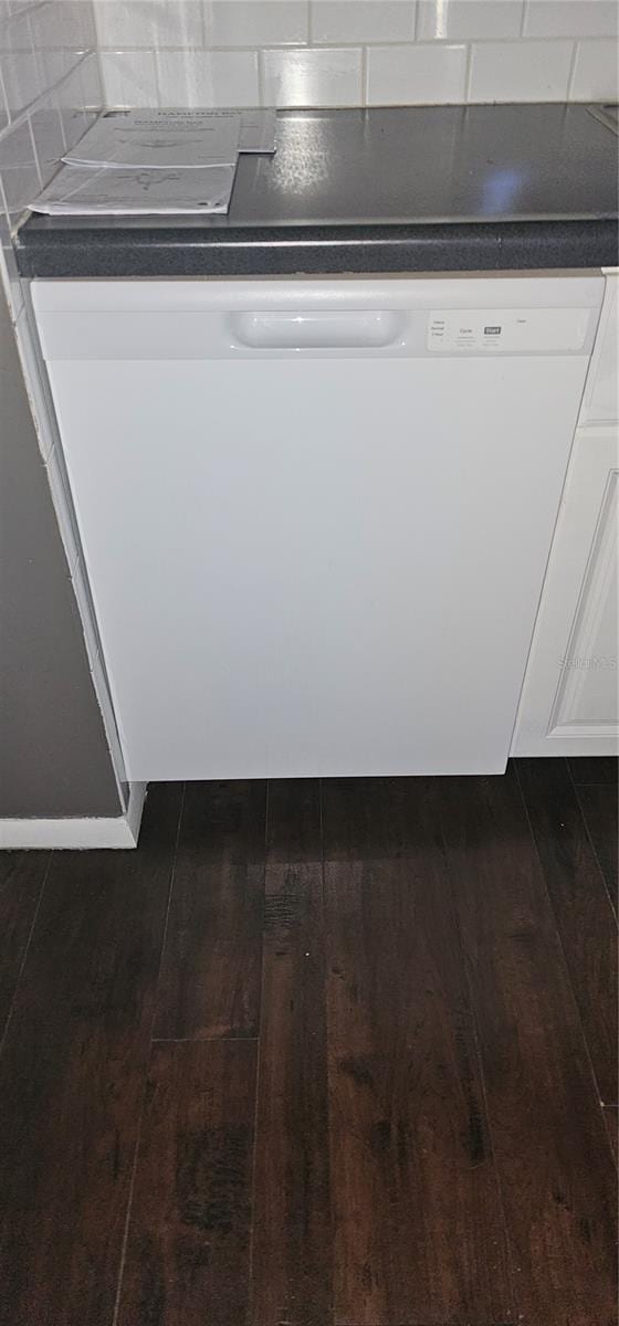 details featuring dishwasher, dark countertops, dark wood-type flooring, white cabinetry, and backsplash