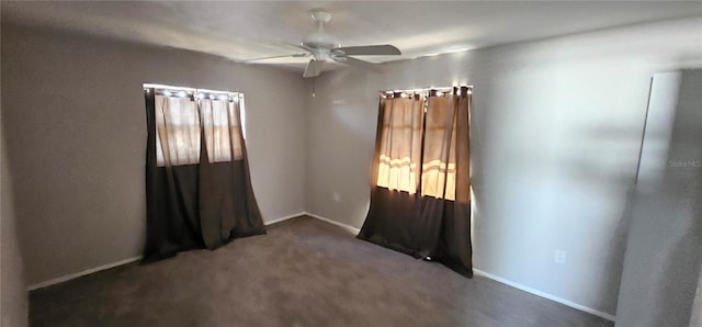 unfurnished room featuring ceiling fan, dark carpet, and baseboards