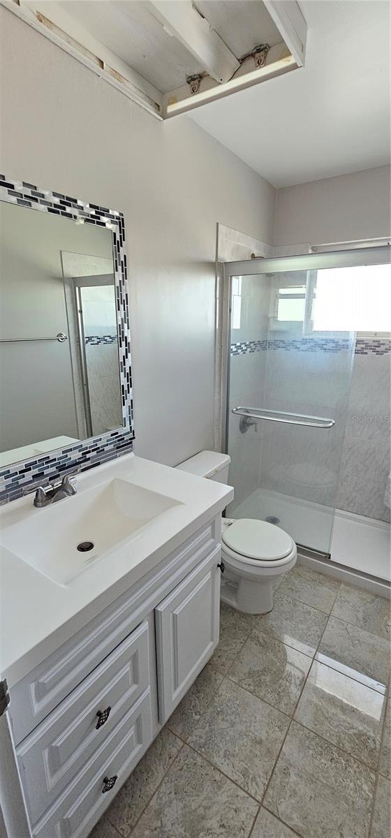 full bathroom featuring toilet, a stall shower, and vanity