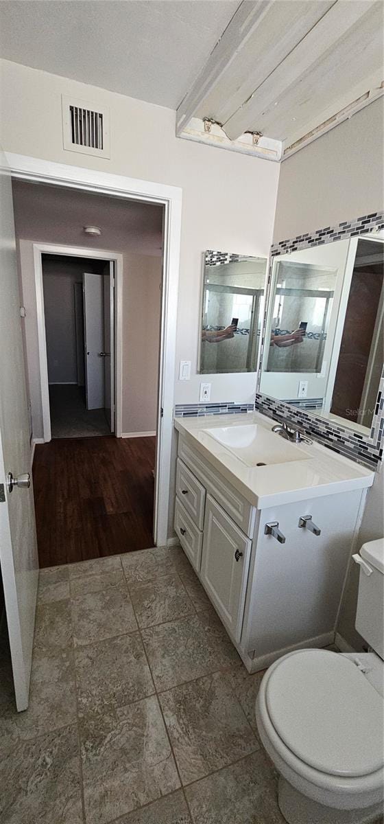 bathroom with toilet, vanity, and visible vents