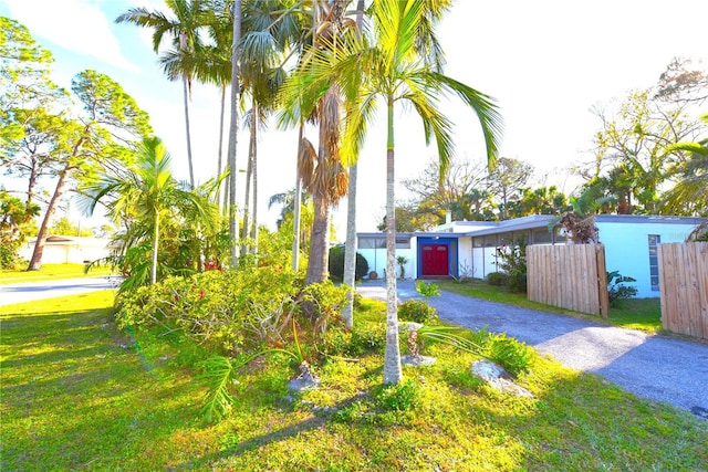 view of front of property featuring driveway, a front lawn, and fence