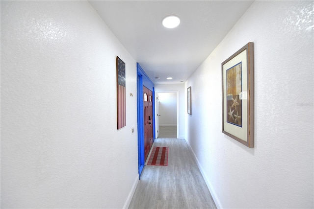 corridor featuring baseboards and wood finished floors