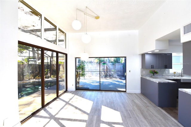 interior space featuring light wood finished floors, a high ceiling, light countertops, and decorative light fixtures