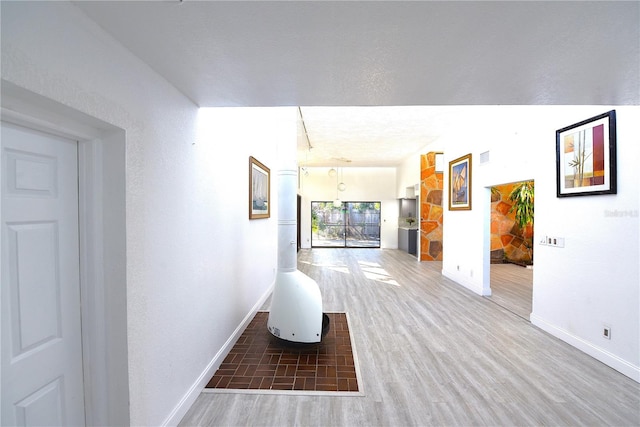 corridor featuring visible vents, baseboards, and wood finished floors