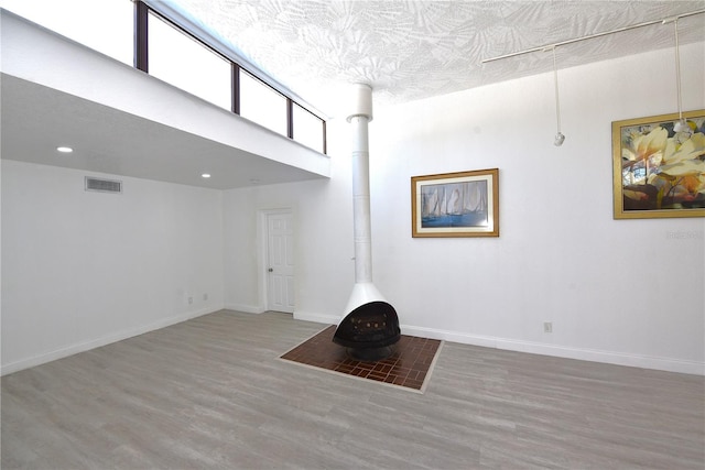 interior space with a wood stove, baseboards, visible vents, and wood finished floors