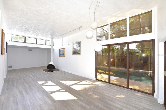 interior space featuring baseboards, wood finished floors, a high ceiling, a textured ceiling, and track lighting