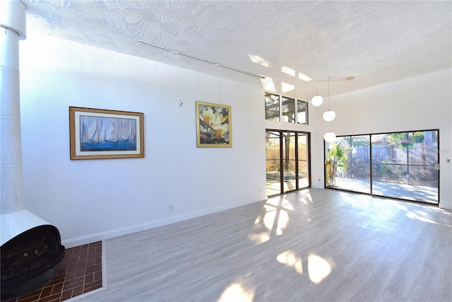 unfurnished living room featuring a textured ceiling, baseboards, and wood finished floors