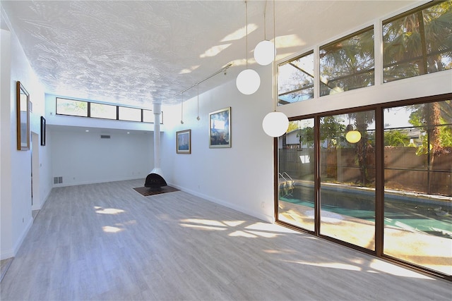 spare room featuring visible vents, wood finished floors, a towering ceiling, and baseboards