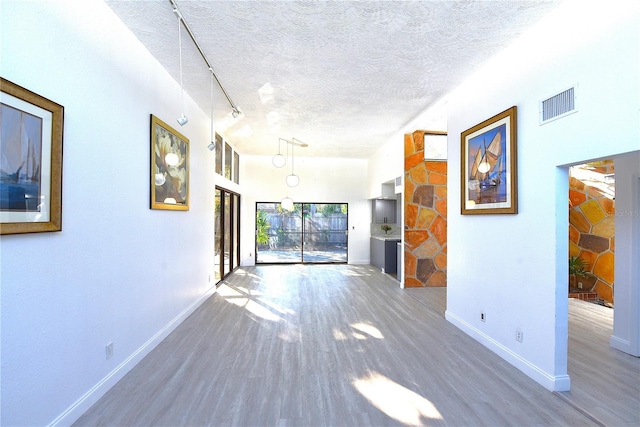 unfurnished room featuring baseboards, a textured ceiling, visible vents, and wood finished floors