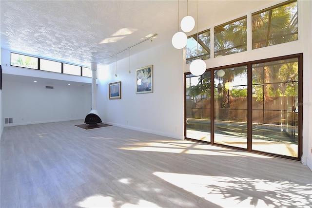 spare room with a textured ceiling, a high ceiling, baseboards, and wood finished floors