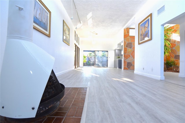 corridor featuring visible vents, baseboards, a textured ceiling, and wood finished floors