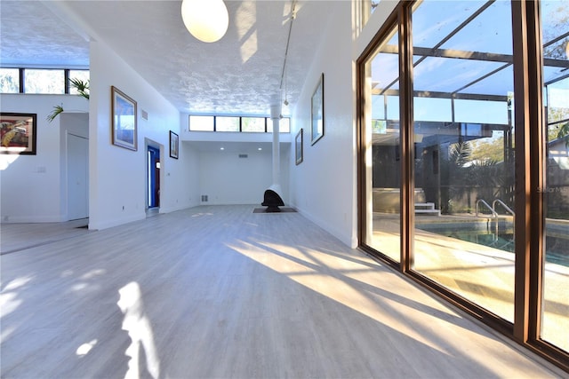 unfurnished living room featuring baseboards, a textured ceiling, and wood finished floors