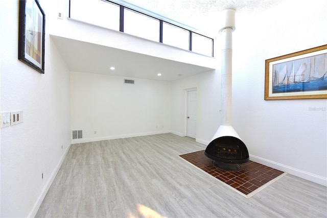 interior space with visible vents, wood finished floors, a wood stove, and baseboards