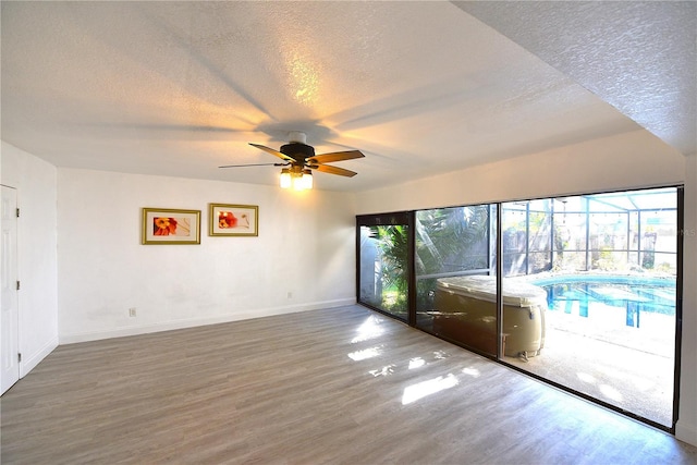 unfurnished room featuring ceiling fan, a textured ceiling, baseboards, and wood finished floors