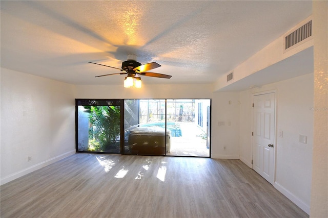 empty room featuring a textured ceiling, wood finished floors, and visible vents