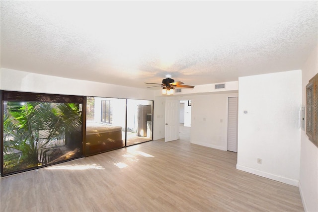 empty room with visible vents, a textured ceiling, baseboards, and wood finished floors