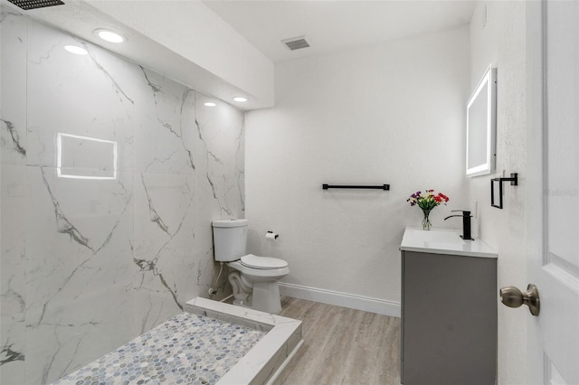 full bath featuring a marble finish shower, visible vents, toilet, vanity, and wood finished floors