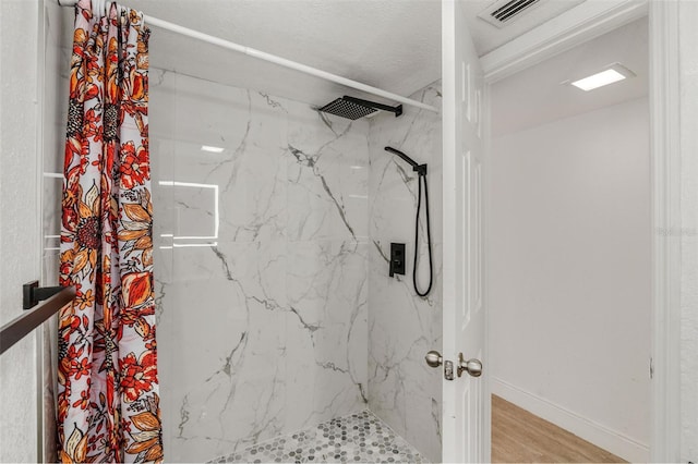 full bath with baseboards, visible vents, a marble finish shower, and wood finished floors