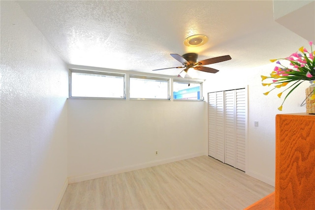 unfurnished bedroom with a textured ceiling, ceiling fan, light wood-type flooring, and baseboards