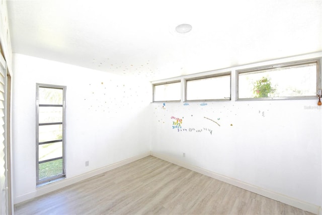 unfurnished room with light wood-type flooring and baseboards