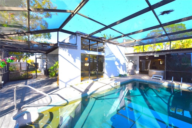 pool with glass enclosure, a hot tub, and a patio