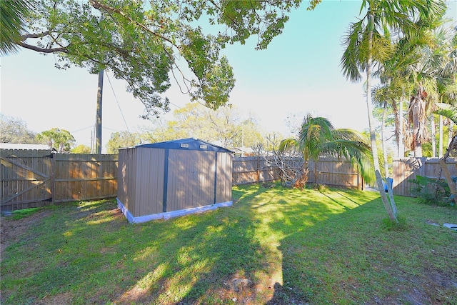 view of yard featuring a fenced backyard, a gate, a storage unit, and an outdoor structure