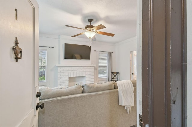 living room with a ceiling fan, a wealth of natural light, a brick fireplace, and ornamental molding