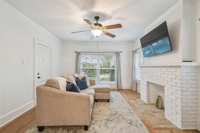 living room with light wood-type flooring, a ceiling fan, and baseboards