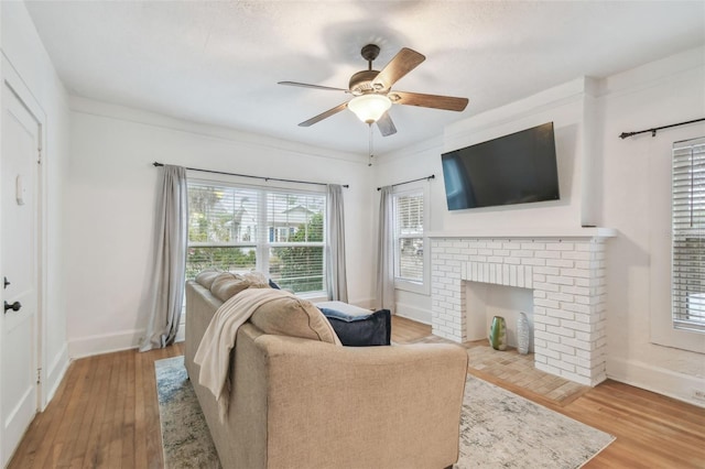 living area with a ceiling fan, a fireplace, baseboards, and wood finished floors