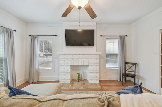 living room with ceiling fan, a fireplace, wood finished floors, and baseboards