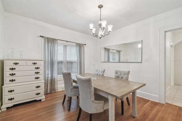 dining area with an inviting chandelier, baseboards, wood finished floors, and ornamental molding