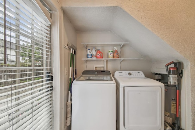 laundry area with a textured ceiling, a textured wall, gas water heater, laundry area, and washing machine and clothes dryer