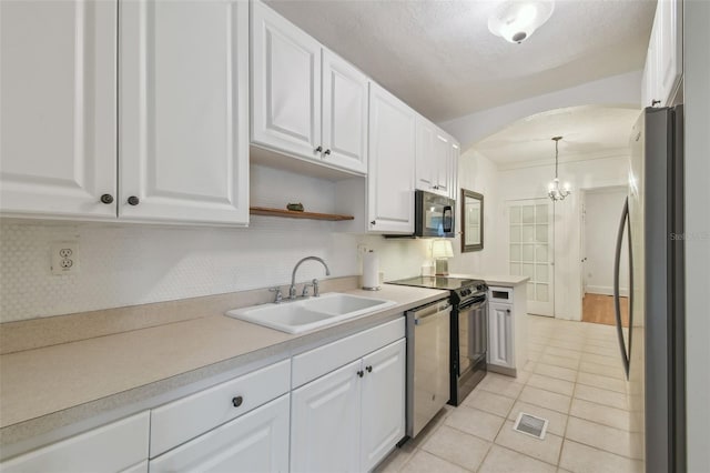 kitchen with hanging light fixtures, appliances with stainless steel finishes, white cabinetry, and a sink