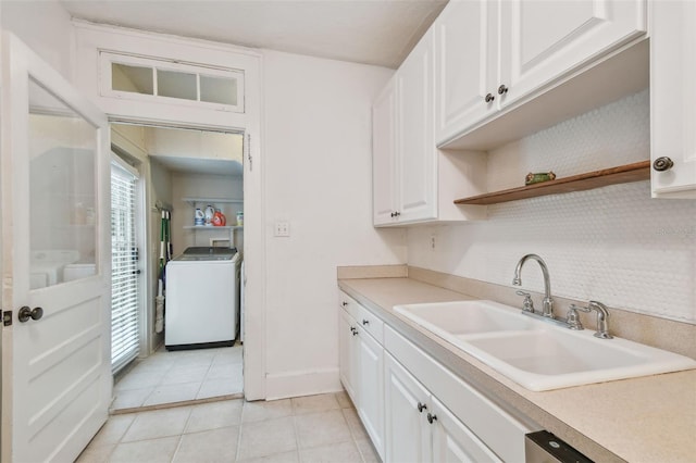 kitchen featuring light tile patterned floors, washer / clothes dryer, light countertops, white cabinetry, and a sink