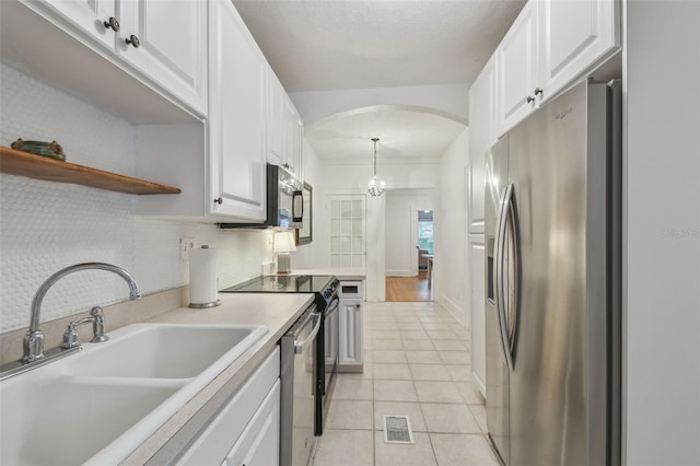 kitchen with appliances with stainless steel finishes, pendant lighting, white cabinets, and a sink