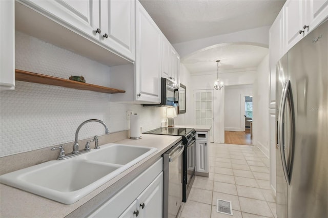 kitchen with a sink, white cabinets, light countertops, appliances with stainless steel finishes, and pendant lighting