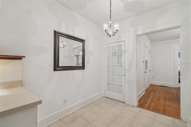 unfurnished dining area with baseboards, ornamental molding, and an inviting chandelier