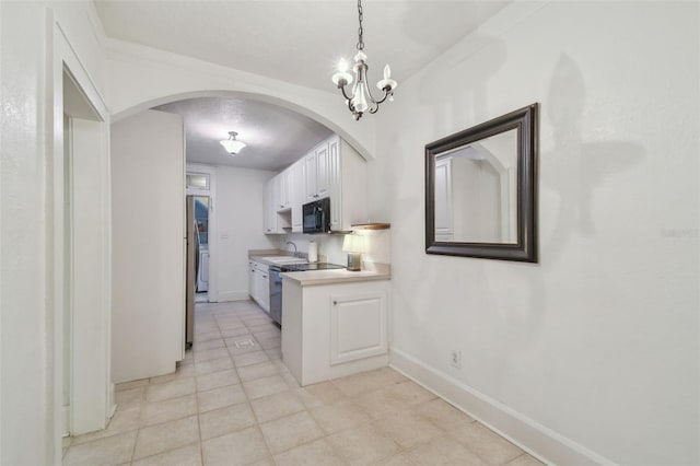 kitchen with black microwave, a sink, white cabinetry, light countertops, and decorative light fixtures