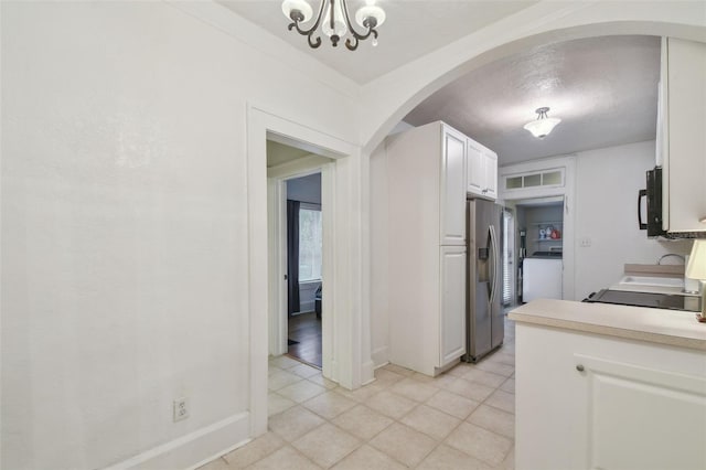 kitchen with stainless steel fridge, white cabinets, range, washer / clothes dryer, and light countertops