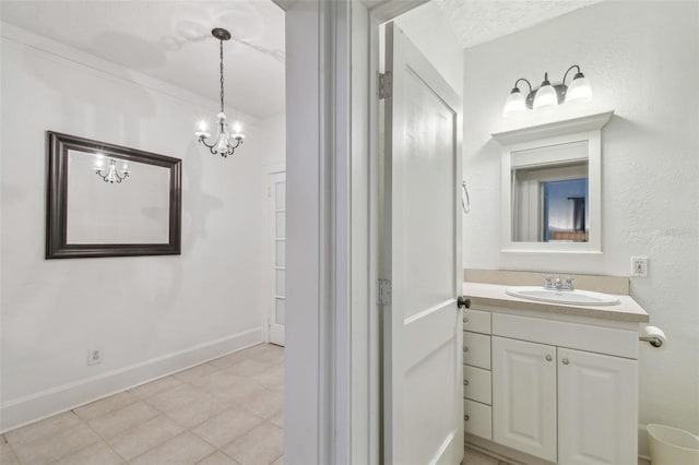 bathroom featuring baseboards, a chandelier, and vanity