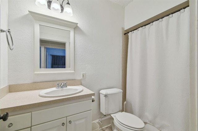 bathroom with curtained shower, a textured wall, vanity, and toilet