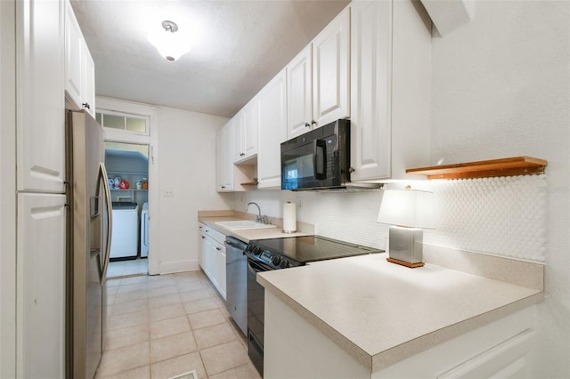 kitchen featuring washing machine and dryer, a sink, white cabinetry, light countertops, and black appliances