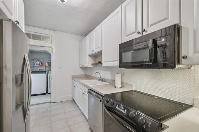 kitchen with independent washer and dryer, light countertops, black appliances, white cabinetry, and a sink