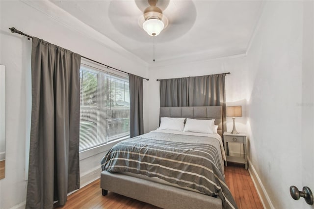 bedroom with crown molding, baseboards, ceiling fan, and wood finished floors