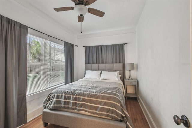 bedroom featuring a ceiling fan, baseboards, and wood finished floors