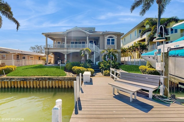 rear view of property featuring stucco siding, a water view, a lawn, stairway, and fence