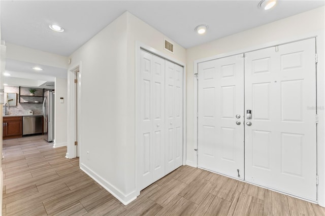 foyer entrance featuring wood finish floors, visible vents, baseboards, and recessed lighting