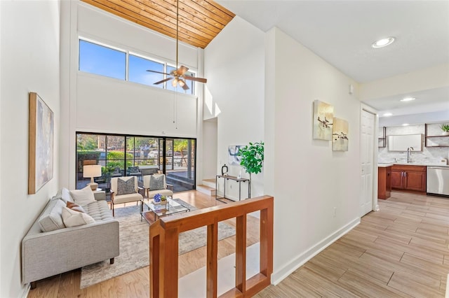 living room with ceiling fan, recessed lighting, light wood-style flooring, and baseboards